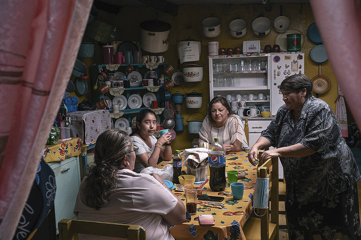 Kvinnor i olika generationer äter och samtalar runt ett köksbord i ett mexikanskt hem.