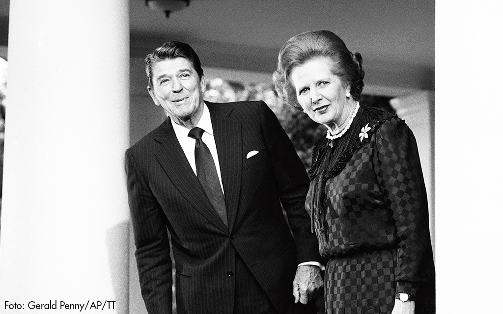 Margeret Thatcher och Ronald Reagan tittar ut mellan Vita Husets pelare.