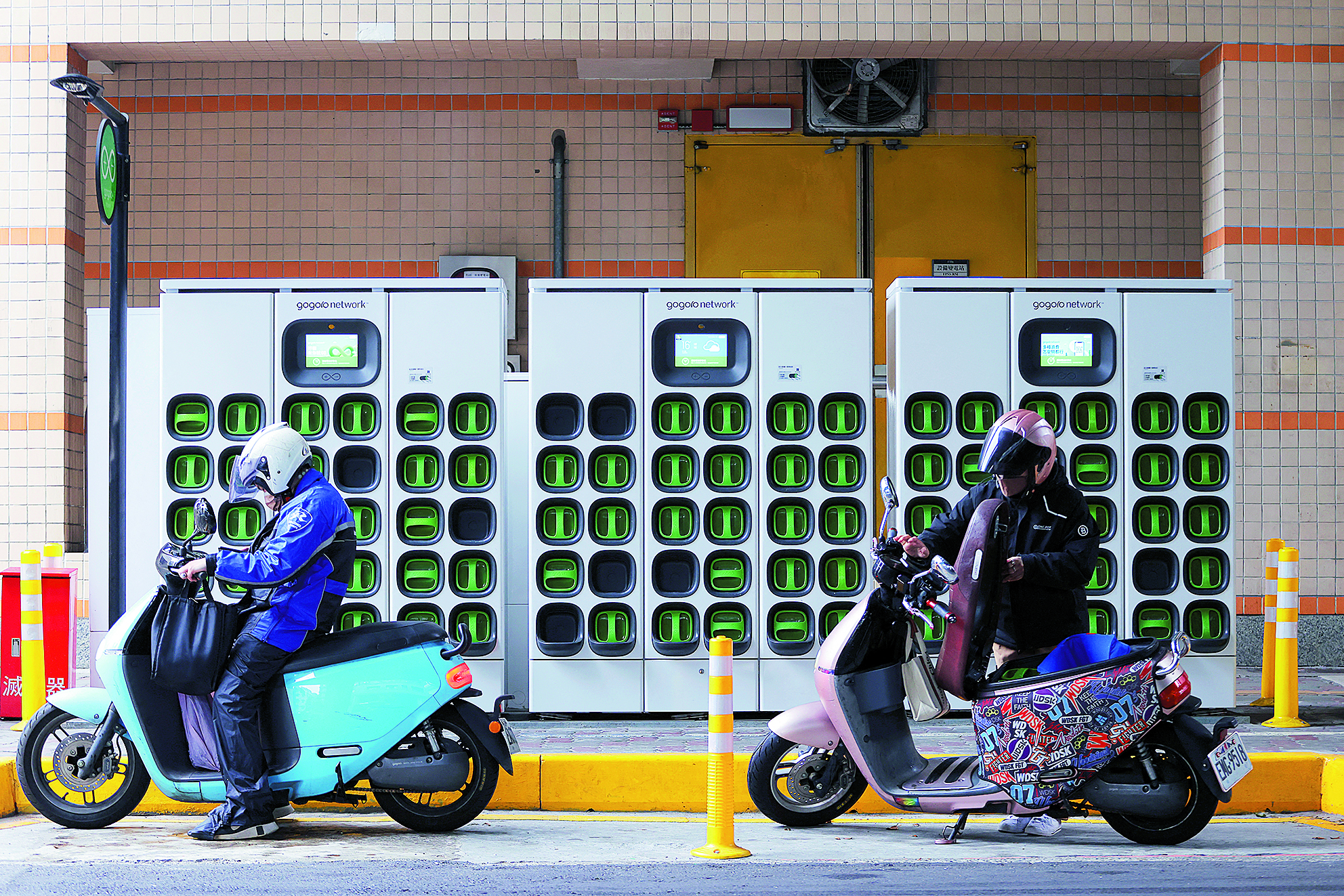 En förare byter batteri till sin skoter vid en batteristation i Taiwan