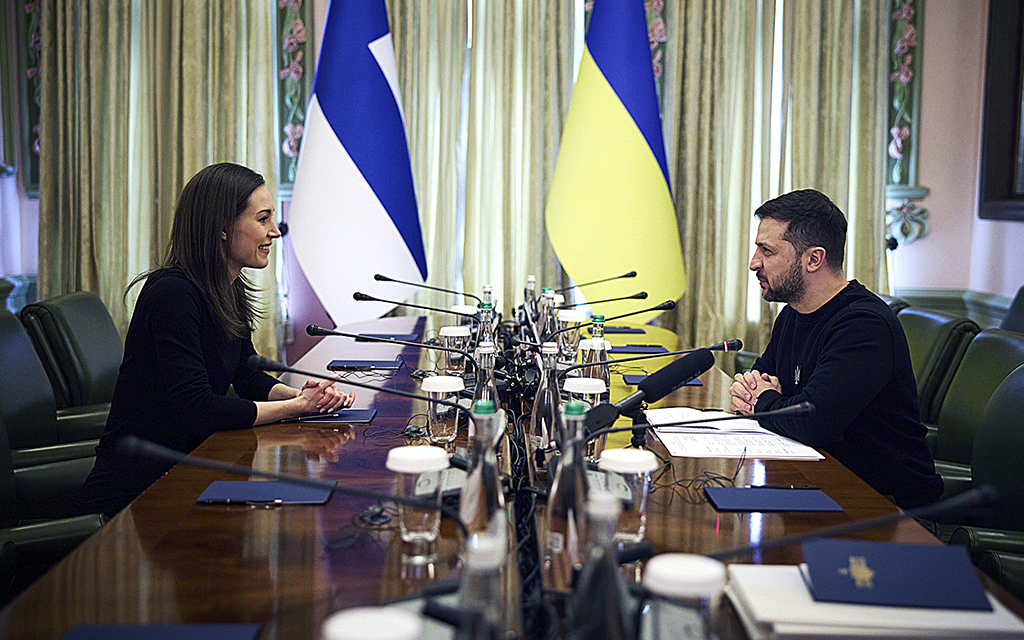 Sanna Marin och Volodymyr Zelenskyy samtalar formellt från varsin sida av ett stort bord.