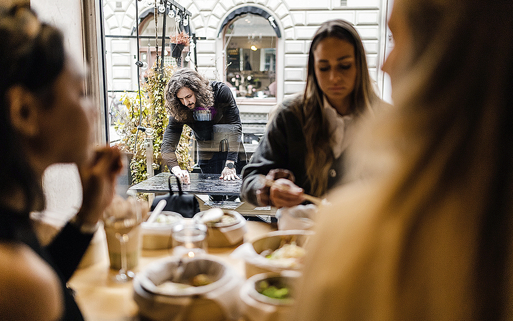 Tre unga kvinnor samtalar och äter på ett kafé