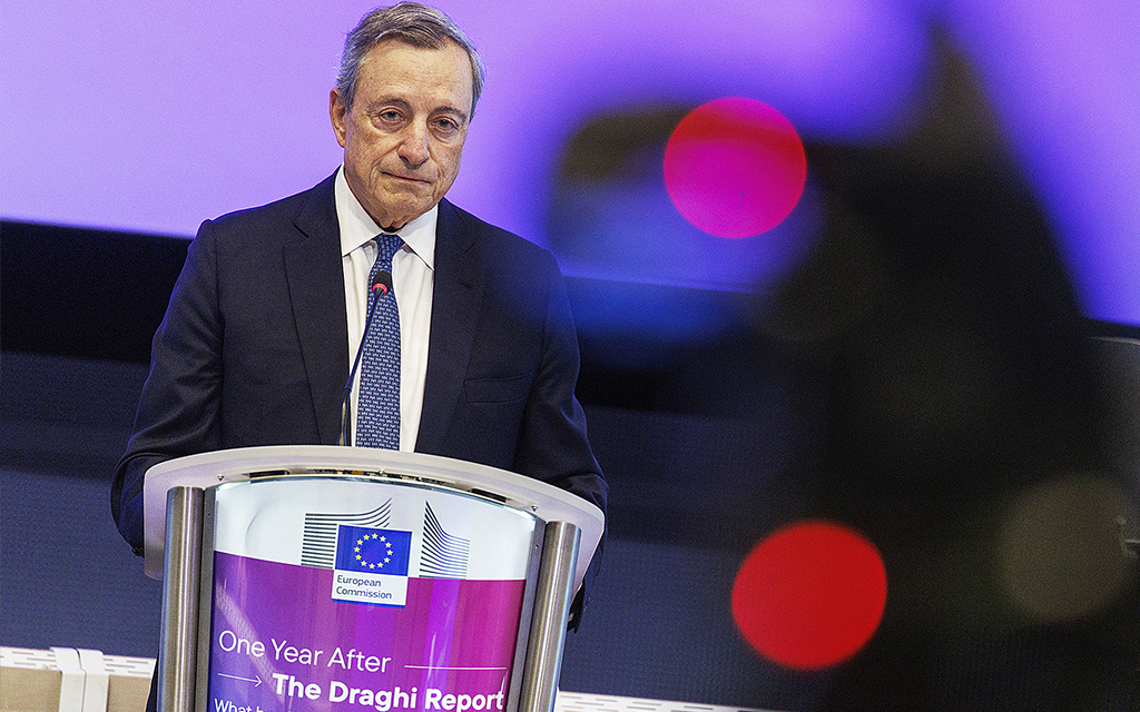 ECB:s tidigare chef Mario Draghi står bakom ett podium och talar till en publik