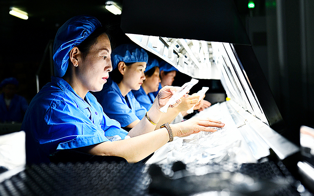 Fyra kvinnor i ett kinesiskt labb utför kvalitetskontroll på läkemedel.