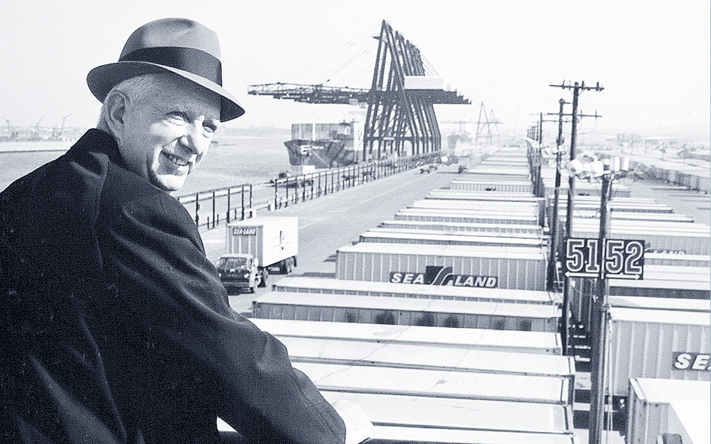 Malcolm McLean porträtterad framför en vy av containrar och lastfartyg.